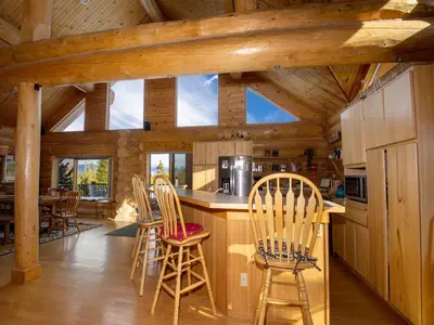 a kitchen with wooden cabinets and chairs in a cabin at Miles Behind Log Cabin in Fraser