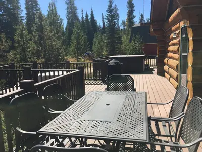 a table and chairs on a deck with a grill at Miles Behind Log Cabin in Fraser