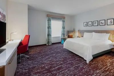 a hotel room with a white bed and a red chair at Hilton Garden Inn Longmont in Longmont