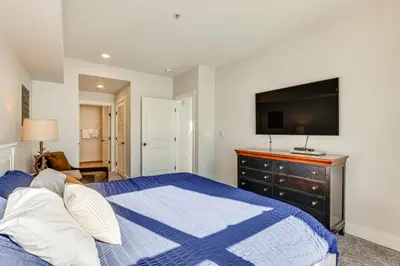 a bedroom with a blue and white bed and a flat screen tv at Ski-InandSki-Out Granby Penthouse with Mountain Views! in Granby