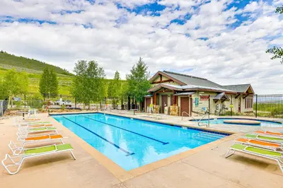a swimming pool with lounge chairs and a house at Ski-InandSki-Out Granby Penthouse with Mountain Views! in Granby
