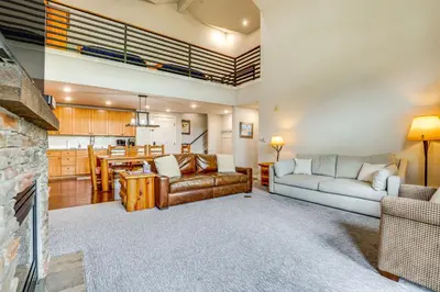 a living room with a couch and a table at Ski-InandSki-Out Granby Penthouse with Mountain Views! in Granby