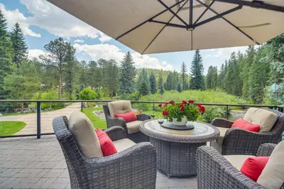 a patio with chairs and a table with an umbrella at Stunning Mtn Views, Private Stream Evergreen Gem! in Evergreen