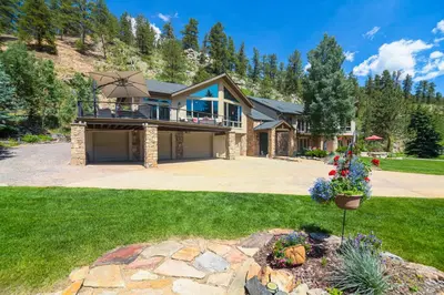 a house with a large porch and a patio at Stunning Mtn Views, Private Stream Evergreen Gem! in Evergreen