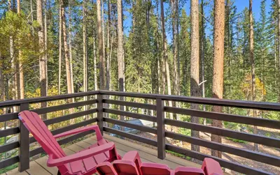 two pink chairs sitting on a deck in the woods at Luxury 4 BR Cabin 2 King Suites on Shuttle Route in Winter Park