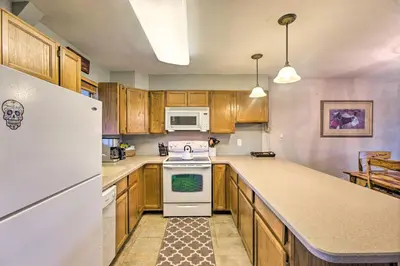 a kitchen with wooden cabinets and a white refrigerator at Winter Park Condo on Bus Route, 2 Blocks to Dtwn! in Winter Park