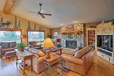 a living room with leather furniture and a stone fireplace at 2 Mi to Skiing Mtn-View Home with Deck in Granby! in Granby
