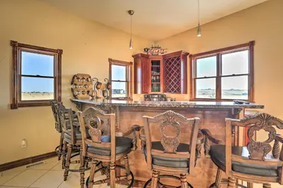 a kitchen with a bar with chairs and windows at 10 Mi to Barr Lake State Park Home with Mtn Views in Hudson