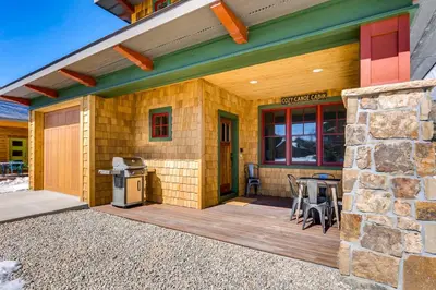 a house with a wooden deck with a stone wall at Dog-Friendly Cabin in the Heart of Grand Lake! in Grand Lake