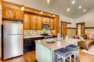 a kitchen with a stainless steel refrigerator and wooden cabinets at Dog-Friendly Cabin in the Heart of Grand Lake! in Grand Lake