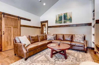 a living room with a leather couch and a table at Dog-Friendly Cabin in the Heart of Grand Lake! in Grand Lake