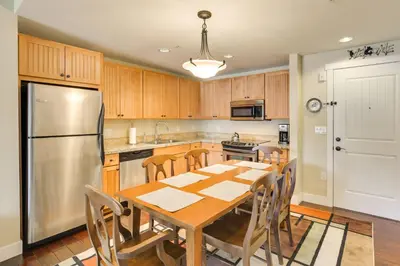 a kitchen with a wooden table and a stainless steel refrigerator at Steps to Ski Lifts Base Camp One Resort Condo in Granby