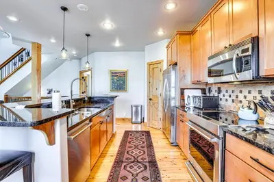 a kitchen with wooden cabinets and stainless steel appliances at Dtwn Frisco Home with Mtn View, 11 Mi to Ski Breck! in Frisco