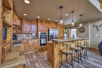 a large kitchen with wooden cabinets and bar stools at Colorado Escape with Mtn Views! 3 Mi to Winter Park in Fraser