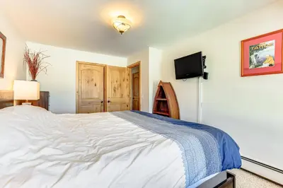 a bedroom with a large bed and a flat screen tv at Dillon Reservoir On-Site Central and Scenic Condo! in Dillon