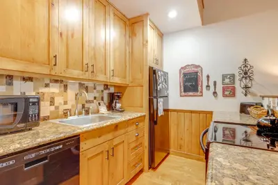 a kitchen with wooden cabinets and a sink at The Inn at Silver Creek Resort Retreat with Balcony! in Granby