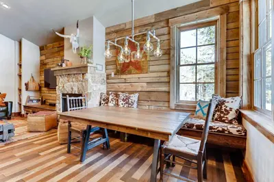 a dining room with a wooden table and a fireplace at 2 Blocks To Grand Lake Downtown Western Cabin! in Grand Lake