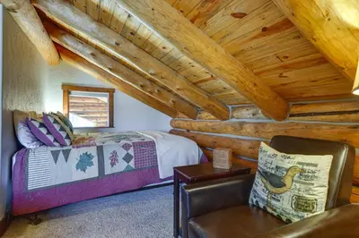 a bedroom in a log cabin with a bed and a chair at Access to Rocky Mtn Natl Park Grand Lake Cabin in Grand Lake