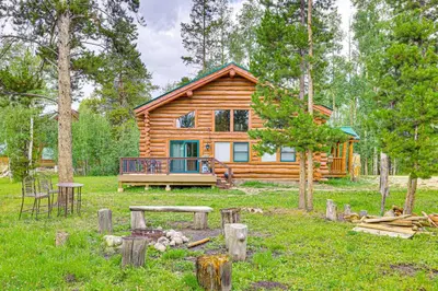 a log cabin in the woods with a picnic table at Access to Rocky Mtn Natl Park Grand Lake Cabin in Grand Lake