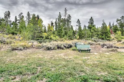 a green bench sitting in a field with trees at Near Lake Granby Grand Lake Townhome with Views in Grand Lake