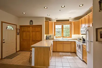 a kitchen with wooden cabinets and a white refrigerator at 7 Mi to National Park Grand Lake Condo with Deck! in Grand Lake
