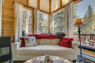 a living room with a white couch and large windows at Idaho Springs Cabin with Hot Tub on Half Acre! in Idaho Springs