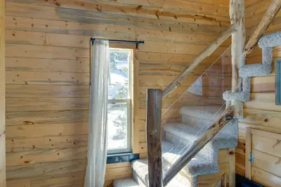 a staircase in a log cabin with a window at Idaho Springs Cabin with Hot Tub on Half Acre! in Idaho Springs