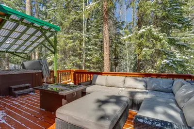 a patio with a couch and a tv on a deck at Idaho Springs Cabin with Hot Tub on Half Acre! in Idaho Springs