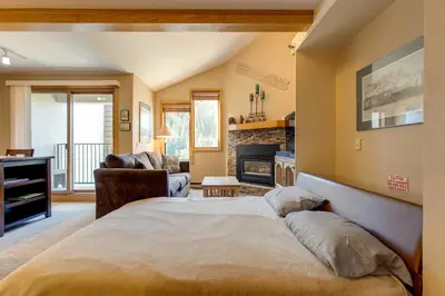 a bedroom with a large bed and a fireplace at Winter Park Ski-InandSki-Out Condo with Mountain Views in Winter Park