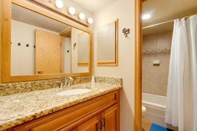 a bathroom with a sink and a mirror and a shower at Winter Park Ski-InandSki-Out Condo with Mountain Views in Winter Park
