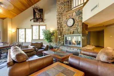 a living room with leather furniture and a stone fireplace at Winter Park Ski-InandSki-Out Condo with Mountain Views in Winter Park