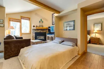 a bedroom with a large bed and a fireplace at Winter Park Ski-InandSki-Out Condo with Mountain Views in Winter Park