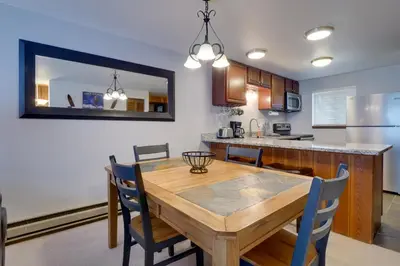 a kitchen and dining room with a wooden table and chairs at Winter Park Condo with Hot Tubs, 4 Mi to Ski Resort! in Winter Park