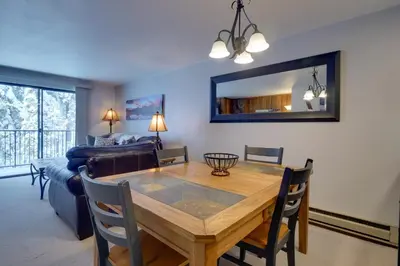 a dining room and living room with a table and a couch at Winter Park Condo with Hot Tubs, 4 Mi to Ski Resort! in Winter Park