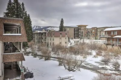 a building in the snow with a bench and buildings at Condo on Fraser River Less Than 4 Mi to Winter Park Resort in Winter Park