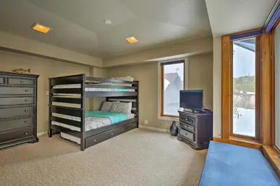 a bedroom with a bunk bed and a dresser and a television at Luxurious Grand Lake Vacation Rental with Hot Tub! in Grand Lake
