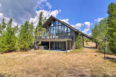 a large house with glass windows on a yard at Luxurious Grand Lake Vacation Rental with Hot Tub! in Grand Lake