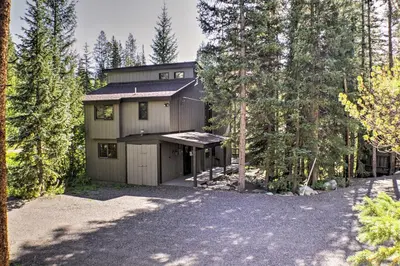 a house with a garage in the middle of trees at Winter Park Cabin - Walk to Main Street and Downtown in Winter Park