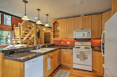 a kitchen with white appliances and wooden cabinets at Winter Park Cabin - Walk to Main Street and Downtown in Winter Park
