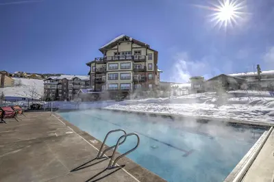 a swimming pool with snow and a building in the background at Ski-InandSki-Out Access Mtn-View Granby Condo! in Granby