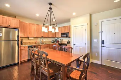 a kitchen with a wooden table and a refrigerator at Ski-InandSki-Out Access Mtn-View Granby Condo! in Granby