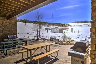 a patio with picnic tables and a grill with a snow covered slope at Ski-InandSki-Out Access Mtn-View Granby Condo! in Granby