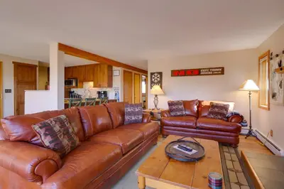 a living room with brown leather couches and a table at Silverthorne Condo Patio, Mtn Views, Pool Access! in Silverthorne