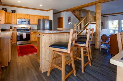 a kitchen with a bar with stools and a staircase at Mtn-View Retreat with Hot Tub in Granby! in Granby