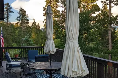 two white umbrellas on a deck with a table and chairs at Mtn-View Retreat with Hot Tub in Granby! in Granby