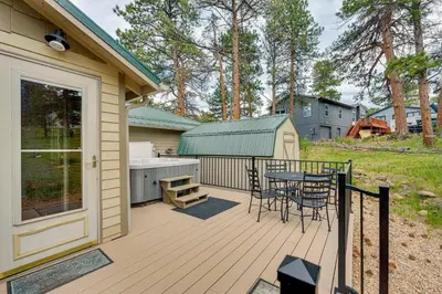 a wooden deck with a table and chairs on it at 2 Mi to Downtown Home with Hot Tub in Estes Park! in Estes Park