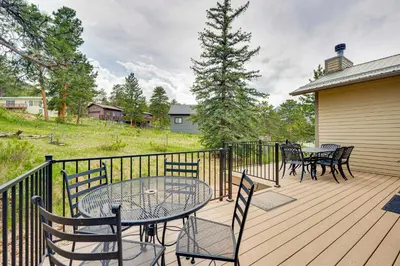 a wooden deck with a table and chairs on it at 2 Mi to Downtown Home with Hot Tub in Estes Park! in Estes Park