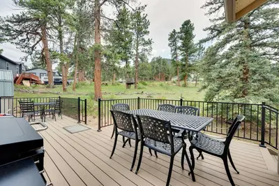 a patio with a table and chairs on a deck at 2 Mi to Downtown Home with Hot Tub in Estes Park! in Estes Park