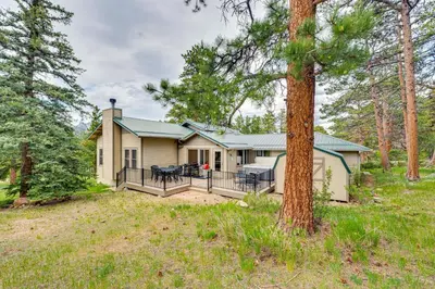 a house with a porch in the woods at 2 Mi to Downtown Home with Hot Tub in Estes Park! in Estes Park