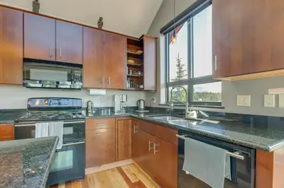 a kitchen with wooden cabinets and a large window at Fraser House with Mtn Views Near Winter Park! in Fraser
